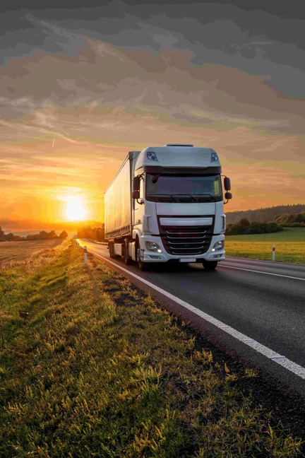 White Truck Driving On The Asphalt Road At Sunset