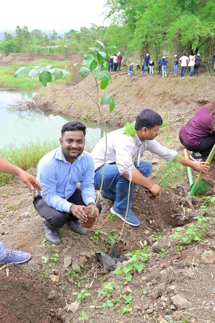 Group Planting Trees By River Bed